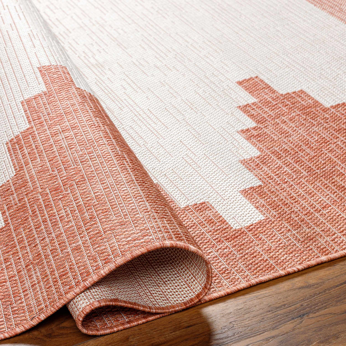 Folded peach polypropylene outdoor rug showing construction